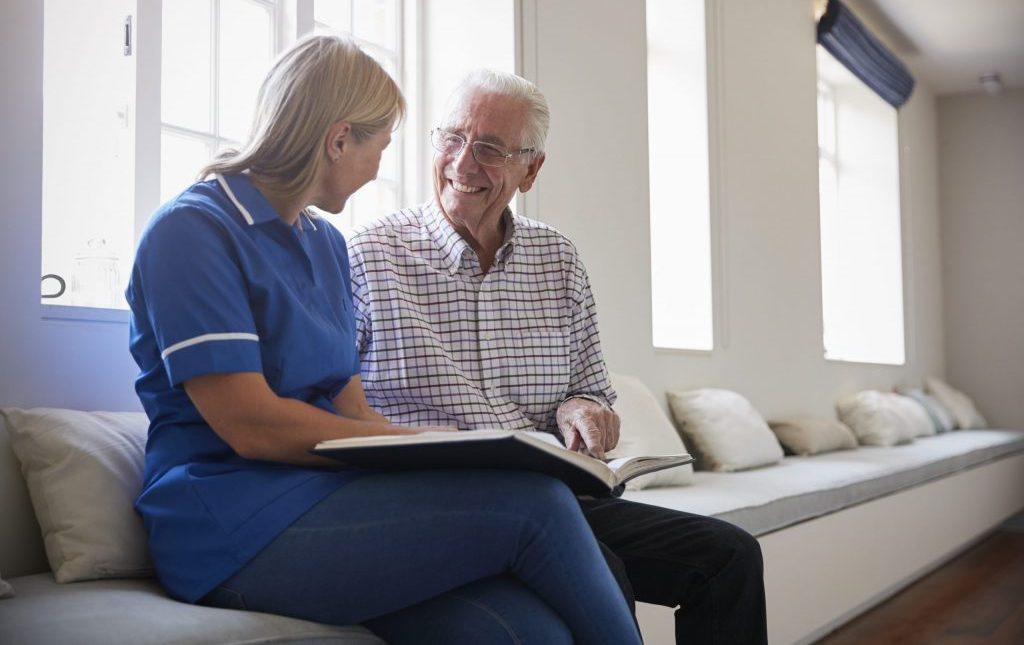 Active Senior talking and sitting with a nurse potentially discussing, and experiencing Providence House Assisted Living Facility