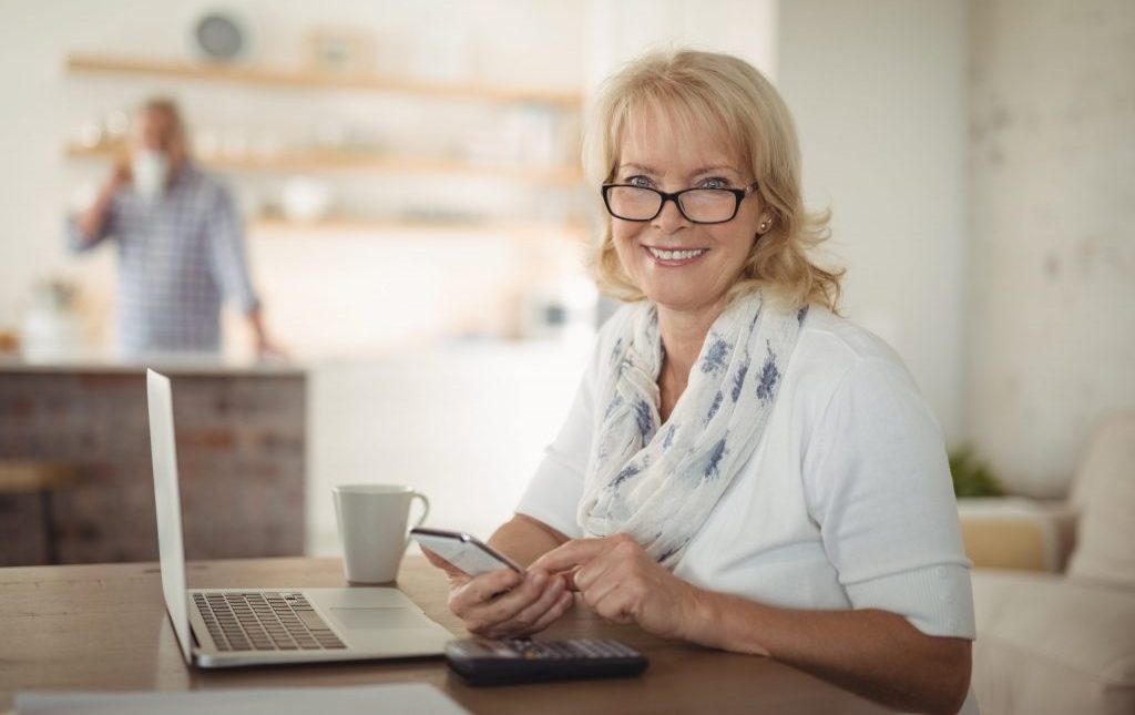 An Active Senior Woman looking at her phone to potentially check providence house promotions
